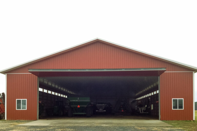 large implement shed with wide doorway and red siding