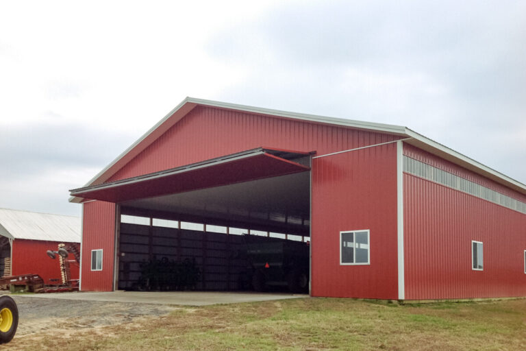 large implement shed with wide doorway and red siding