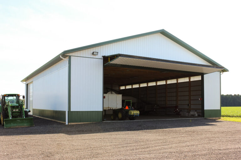 large implement shed with wide doorway and white siding