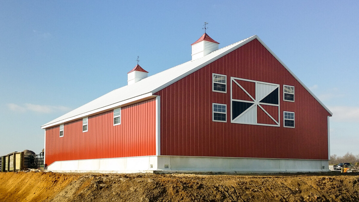 end view of large implement shed with red siding built by byler builders