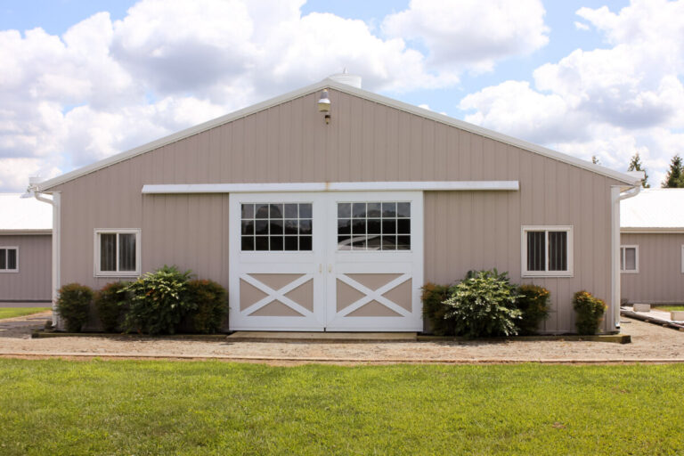 sliding doors at the entrance of a horse barn with brown siding