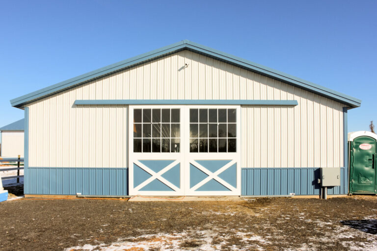 sliding doors at the entrance of a horse barn with light siding